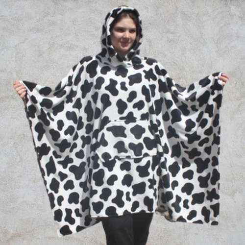Girl wearing hooded blanket in a black and white cow print fleece fabric with front pocket