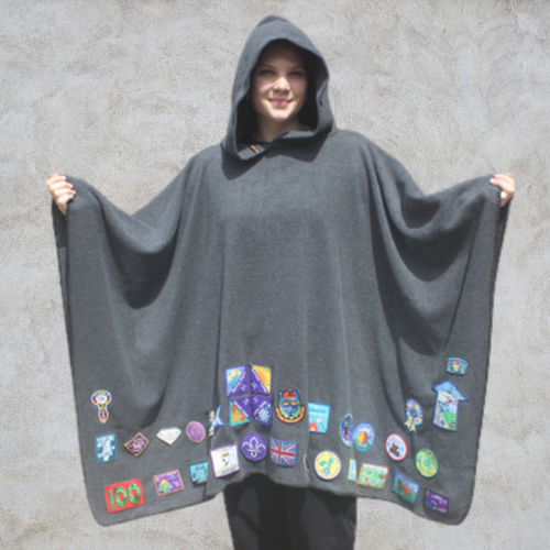 Girl wearing grey hooded blanket camp blanket badge blanket with scout badges sewn on